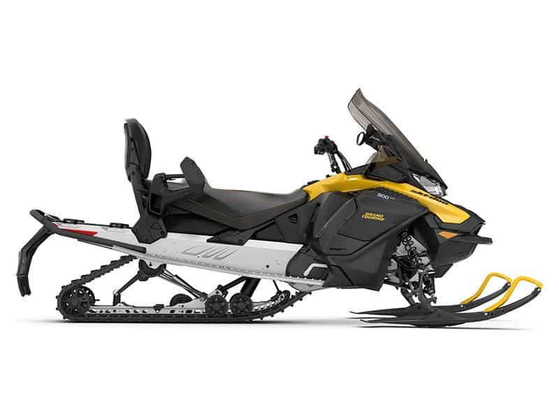 A yellow and black snowmobile with a windshield, two front skis, a rear track, and a seat for two riders, viewed from the side against a white background.